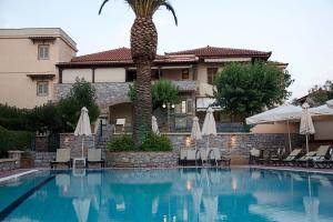 a swimming pool with a palm tree in front of a building at Madena Apartments in Stoupa