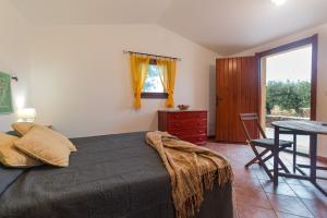 a bedroom with a bed and a table and a window at S'Ulumu in Dorgali