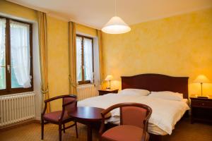 a bedroom with a bed and a table and chairs at Hotel de Bahyse in Blonay