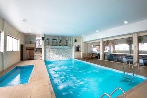 a swimming pool with blue water in a house at Hotel Guarany in Águas de Lindoia