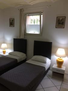 two beds in a room with a window and two lamps at VILLA ALMA 2 in Bologna