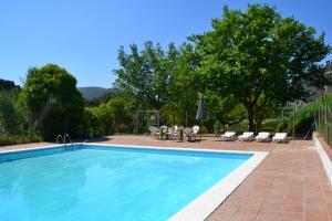 a swimming pool with chairs and a table and a umbrella at Masia Molí de Tartareu in Tartareu