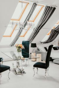 Coco Chanel Boutique Apartment في برنو: غرفة معيشة بها المناور وطاولة وكراسي زجاجية
