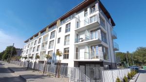 a white building with a fence in front of it at Porta Mare Apartamenty Słoneczne Tarasy in Dziwnówek