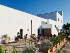 un patio avec des chaises et des tables en face d'un bâtiment dans l'établissement Masseria Fabrizio, à Otrante
