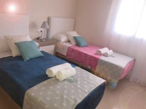 マニルバにあるNew ! Manilva Playa SPA Resort 2/2 sea view apartmentのベッド2台とオットマン2台(タオル付)が備わるお部屋です。