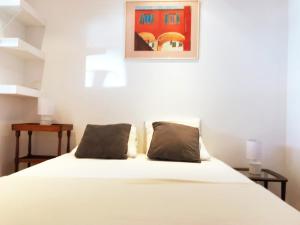 um quarto com uma cama branca e 2 almofadas em Le Palmyre em Cassis