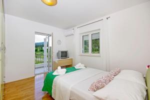 a white bedroom with a bed and a television at Luxurious, modern and spacious apartment with terraces in Tugare