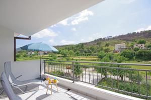 a balcony with a chair and an umbrella at Luxurious, modern and spacious apartment with terraces in Tugare