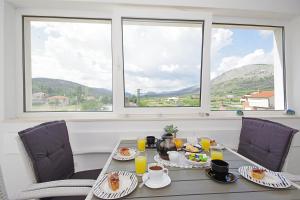 a table with breakfast food and two large windows at Luxurious, modern and spacious apartment with terraces in Tugare