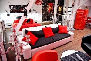 シュチェチンにあるIn the Attic Apartmentsのリビングルーム(赤い枕と白いソファ付)