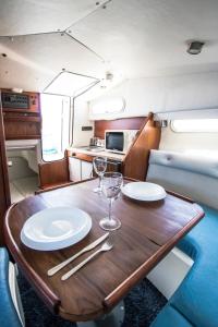 a wooden table with two plates and wine glasses on it at Cozy boat to unwind by the ocean in Puerto Calero