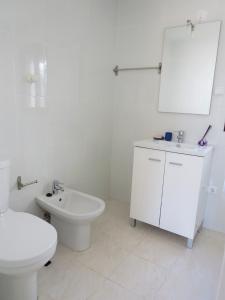 La salle de bains blanche est pourvue de toilettes et d'un lavabo. dans l'établissement Casa dos Avos, à Ovar