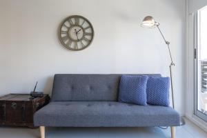 eine blaue Couch in einem Wohnzimmer mit einer Uhr an der Wand in der Unterkunft Gorriti Palace in Buenos Aires