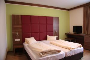 una camera da letto con un letto grande con testiera rossa di Sporthotel Mölltal a Flattach