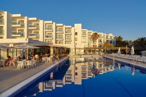 a resort with a pool with tables and chairs and a building at Aparthotel Nereida in San Antonio Bay