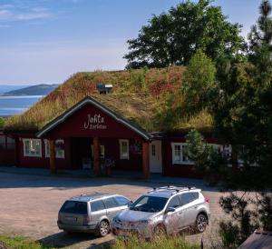 two cars parked in front of a building with a grass roof at Jækta Fjordstue in Mosvik