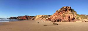 a sandy beach with a large rock cliff at Montinho Boutique Studio in Benagil