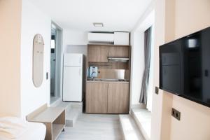 a small kitchen with a refrigerator and a television at Amalia Rooms Sea View in Nea Vrasna
