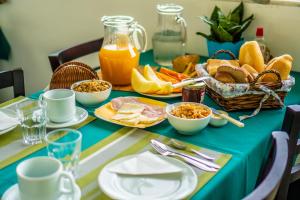 a table with a blue table cloth with breakfast foods and orange juice at Pousada Piquara in Mangaratiba