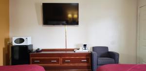 a living room with a chair and a tv on a wall at Super 7 Motel in Sedalia