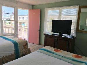 a bedroom with two beds and a tv and a window at Skylark Resort Motel in Wildwood