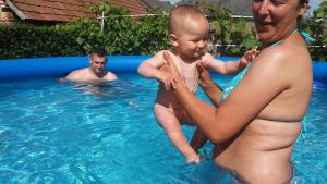 Ein Mann, der ein Baby im Pool hält. in der Unterkunft Rózsa apartman in Lenti
