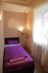 Un dormitorio con una cama morada y una ventana. en Downtown-home in the heart of old Tbilisi, en Tiflis