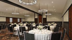 una sala de banquetes con mesas y sillas blancas y lámparas de araña en The Craftsman Inn & Suites, en Fayetteville