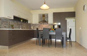 a kitchen with a table and chairs and a white refrigerator at Chrissi's house with garden and sea view in Kissamos