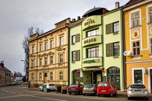 ein Gebäude mit Autos, die davor auf einer Straße geparkt sind in der Unterkunft Hotel Rieger Garni in Jičín