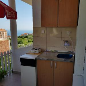 a kitchen with a counter with a sink and a balcony at Apartments Draga in Budva