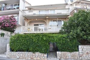 un edificio con balcone e alcuni cespugli di Ivančica Apartments a Tisno (Stretto)