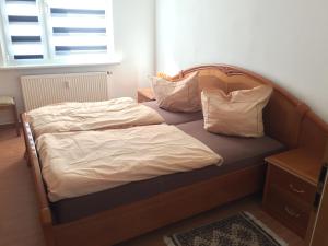 een bed met een houten hoofdeinde en kussens erop bij Ferienwohnung Amanda in Stützerbach