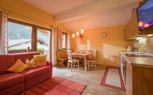 a living room with a couch and a kitchen with a table at Landhaus Gasser in Mayrhofen