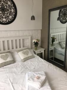 a bedroom with a white bed and a mirror at kameralny apartament in Olsztyn