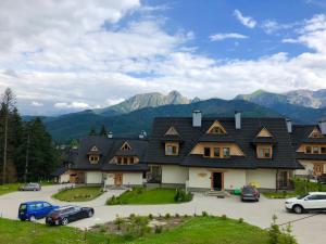 a large house with mountains in the background at Apartament KościeliSKI in Kościelisko