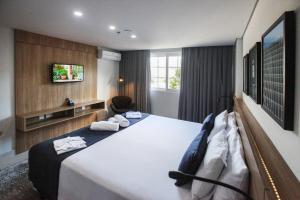 a hotel room with a large bed and a tv at Apto Itaipava Granja Brasil in Itaipava