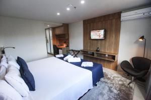 a bedroom with a large white bed and a chair at Apto Itaipava Granja Brasil in Itaipava +15 photos