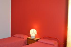 Habitación roja con 2 camas y una lámpara en una mesa en Casa vacanze Arzana, en Arzana