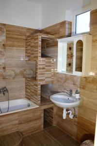 a bathroom with a sink and a bath tub at Főnix Apartmanház in Hajdúszoboszló +66 photos