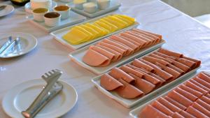 einen Tisch mit Platten verschiedener Arten von Lebensmitteln in der Unterkunft Hotel Pinheirinho in Curitiba