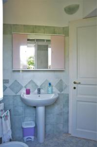 a bathroom with a sink and a mirror and a toilet at Sa Teria Village - Appartamenti - in Tertenìa