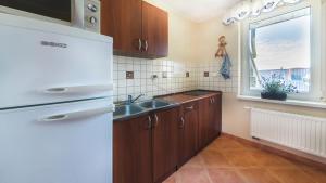 a kitchen with wooden cabinets and a sink and a window at Villa Malva in Karwia