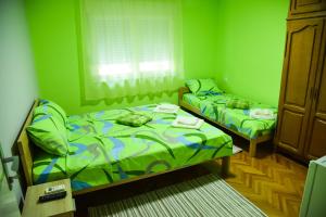 2 letti in una camera con pareti verdi di PRENOĆIŠTE PILOT a Niš