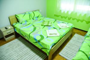 a bedroom with a bed with a green comforter at PRENOĆIŠTE PILOT in Niš
