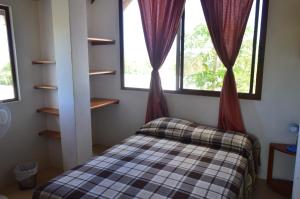 1 dormitorio pequeño con 1 cama y 2 ventanas en Casa de Lelia en Floreana
