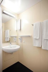 La salle de bains est pourvue d'un lavabo, d'un miroir et de serviettes. dans l'établissement Gasthaus Mooshäusl, à Hebertshausen