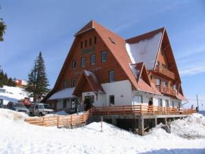 a large wooden building with snow on the ground at Súgó Panzió Madarasi Hargita in Izvoare