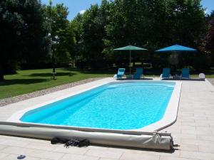 une grande piscine avec des chaises et des parasols bleus dans l'établissement Chez Jousseaume Chambre d'Hôtes et Gites, à Saint-Ciers-Champagne